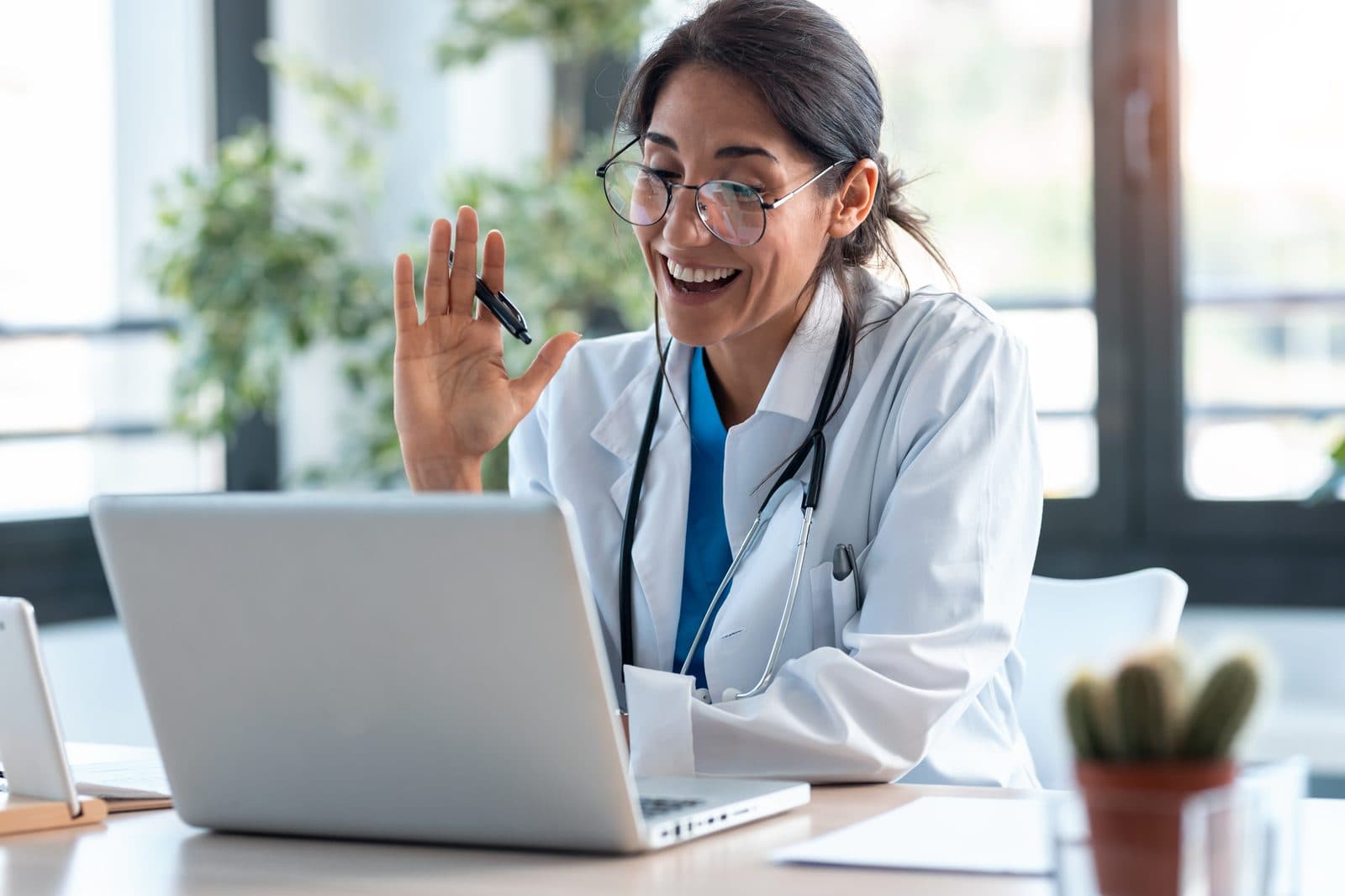 Médica acenando durante consulta por vídeo